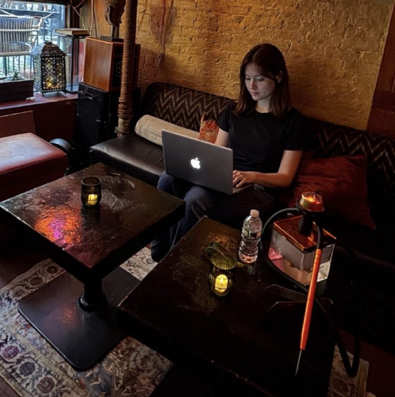 Cozy Cafe East Village woman working on laptop in a dimly lit hookah lounge on East 1st Street