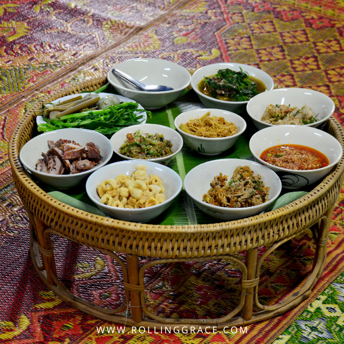 Round Khantoke tray loaded with Northern Thai dishes including curry sticky rice and vegetables in Chiang Mai