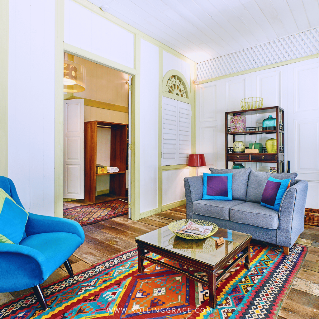 White Penang House living room with a blue sofa, armchair and bright woven rug at Temple Tree Resort Langkawi