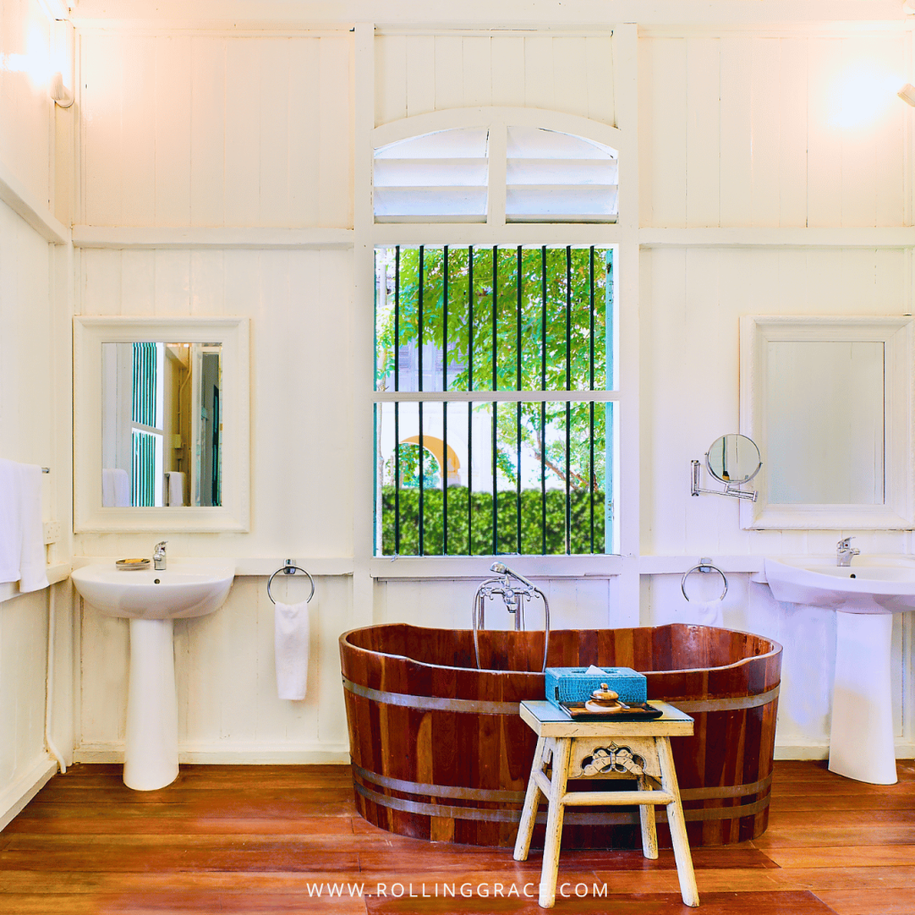 Wooden bathtub beneath a barred window in a Penang House bathroom at Temple Tree Resort Langkawi