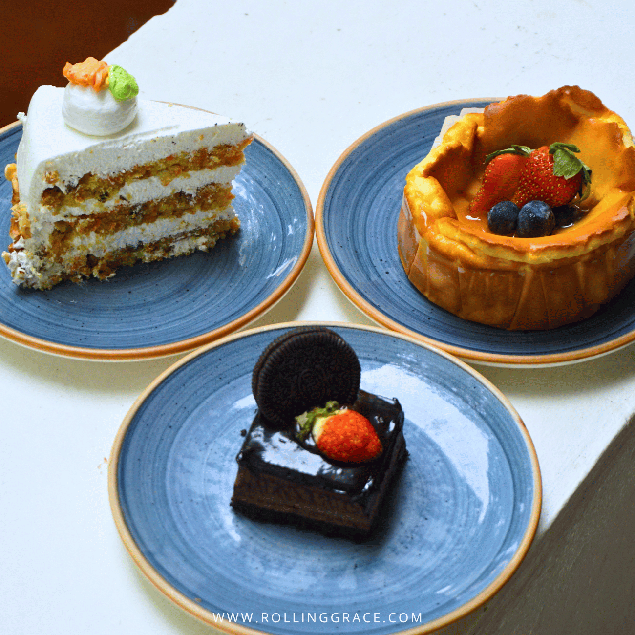 Carrot cake, a berry-topped tart and a chocolate cake on blue plates at the Reception Café, Temple Tree Resort Langkawi