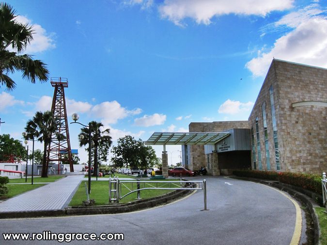 Petroleum Museum building and curved driveway on Canada Hill Miri, Sarawak, with the oil derrick and palms nearby