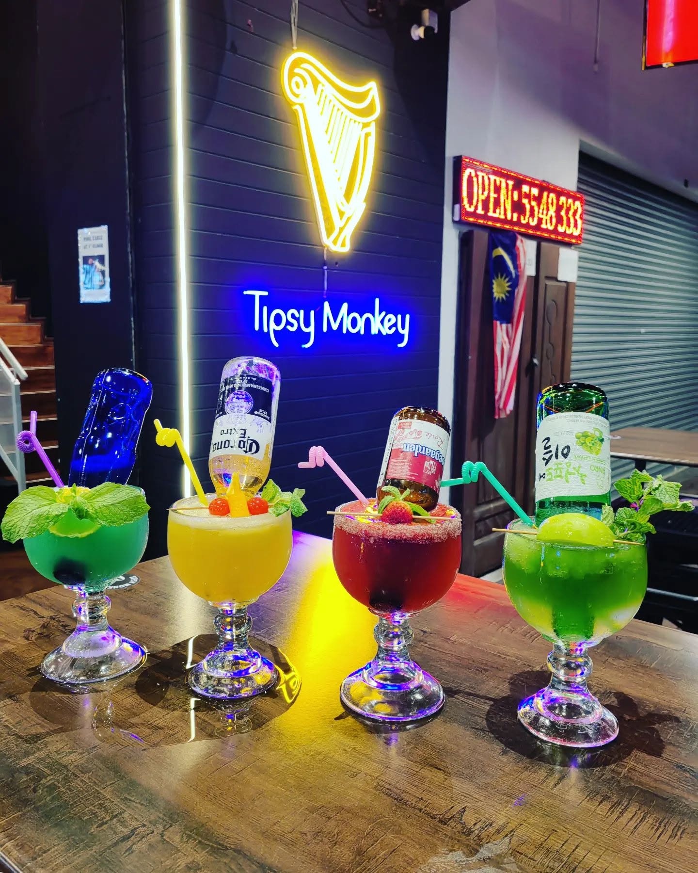 Colourful cocktails lined up on the bar beneath the Tipsy Monkey neon sign in Sutera Utama, Johor Bahru