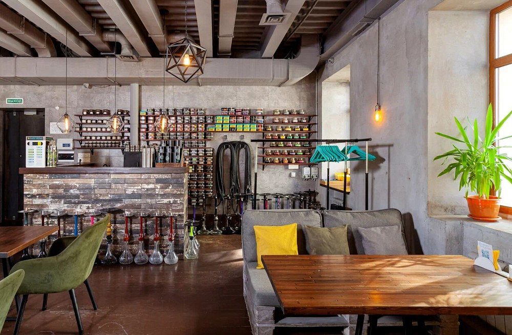 Loft lounge with exposed wooden beams, tobacco shelves and green chairs at Biblioteka Shisha Lounge, Arbat, shisha in Moscow