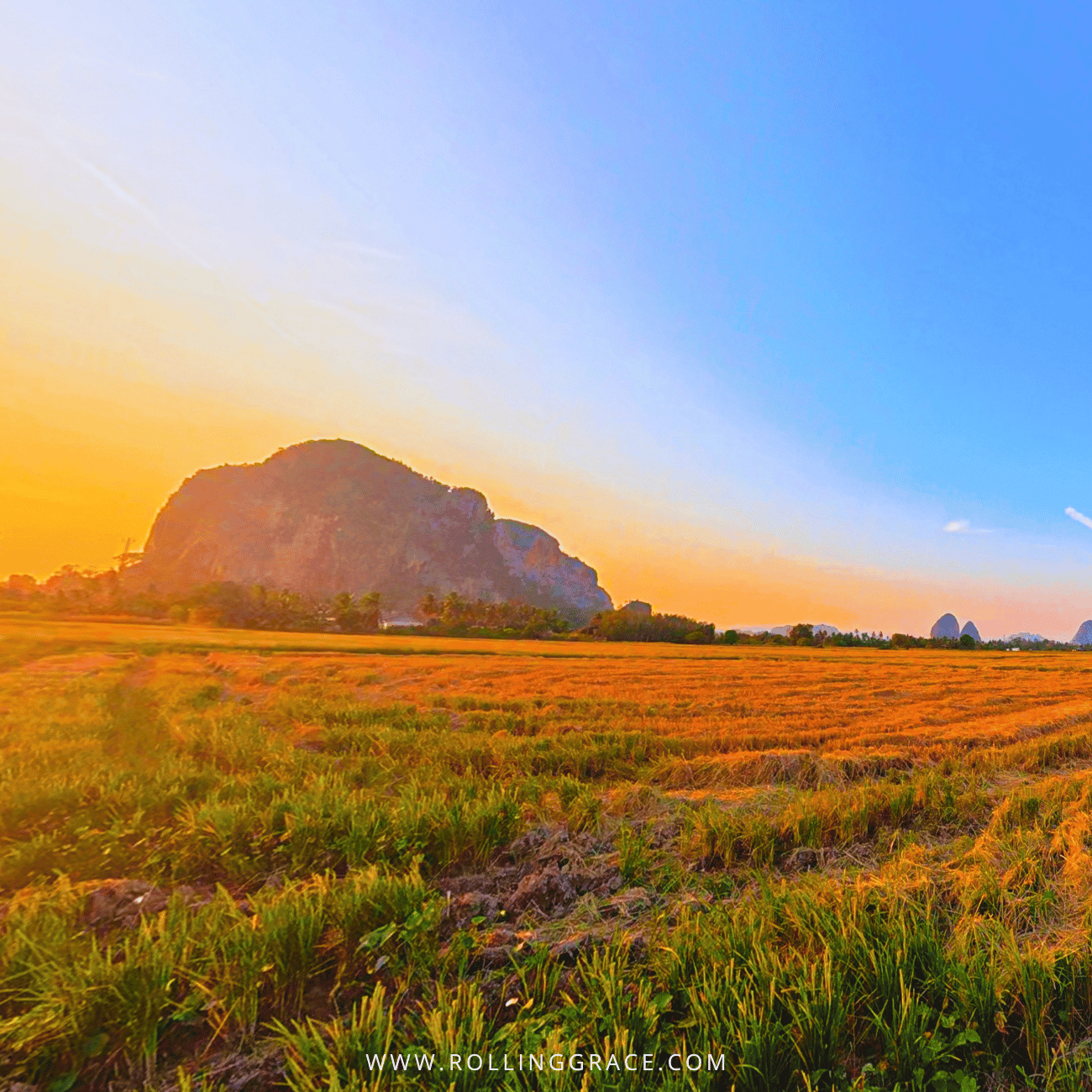 Bukit Chabang's limestone hill rising above golden paddy fields under an orange sky, a hike among things to do in Perlis